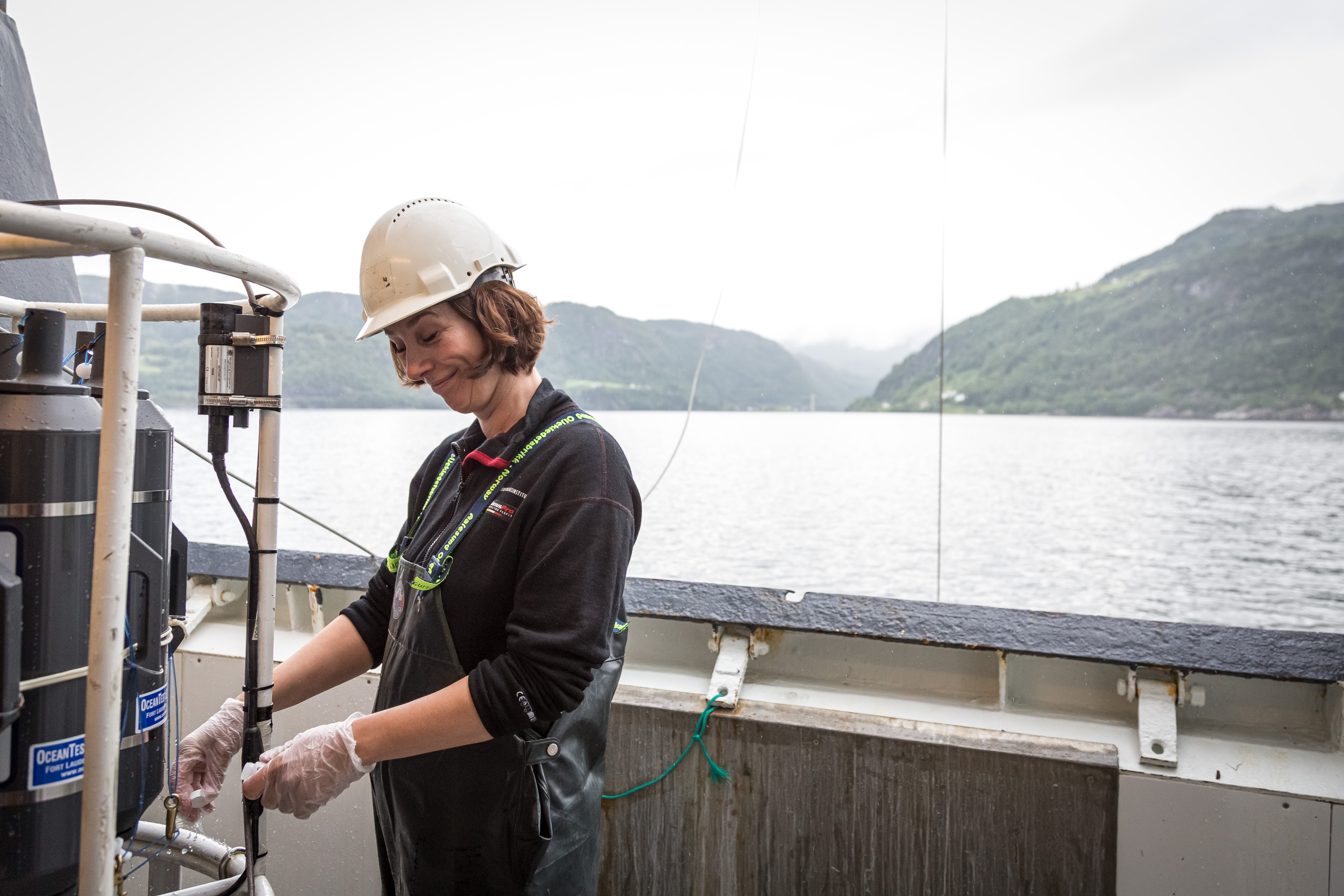 Bilde av person som jobber med å ta vannprøver fra tanker med vann som er hentet opp på dekk fra ulike dyp.