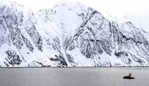 Ubemannet farkost Frigg ligger på blått hav i nordnorsk fjord. Fjell i bakgrunnen og pent vær.